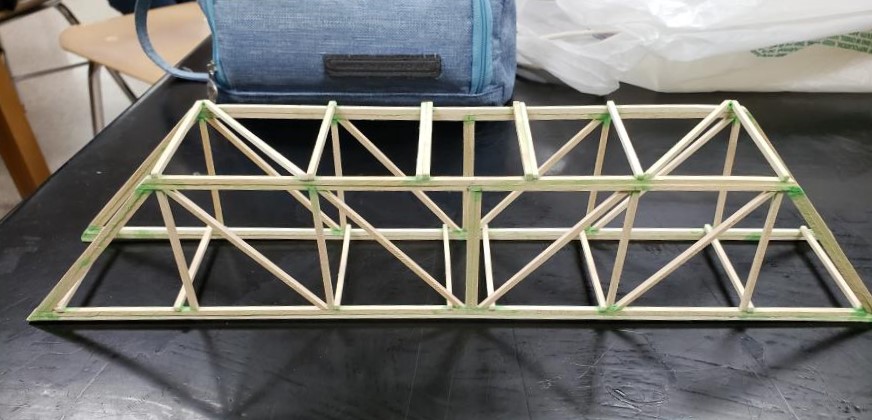 a picture of a truss bridge I made out of wood sticks, on the table